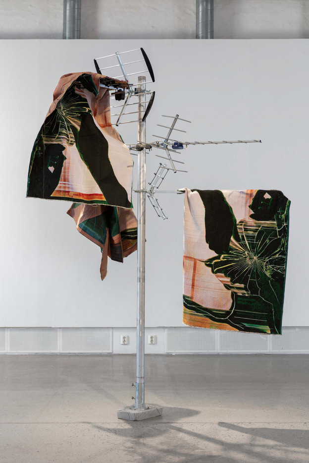 Skulptur beståede av tre digital vev drapert over tv antenner, motiv på vevene er en hånd som berører en knust skjerm.