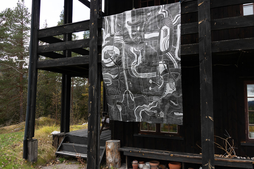 Foto av tresnitt på papir, hengende fra 2. etasje på huset jeg bodde i mens jeg laget tresnittet, med utsikt mot Vinjevann.