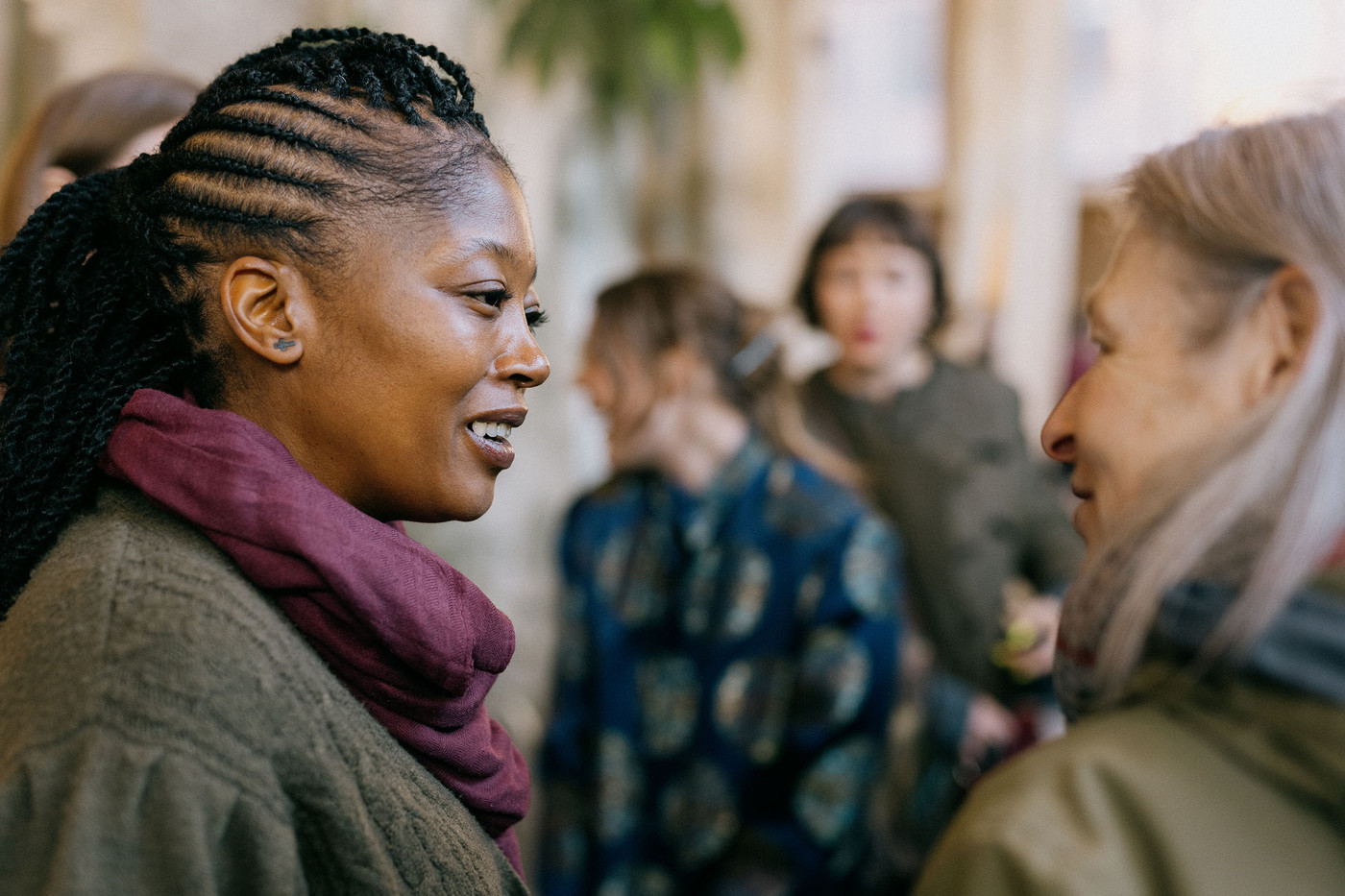 To kvinner snakker sammen. I bakgrunnen flere mennesker.