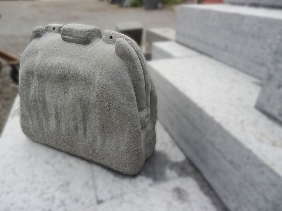 En håndveske hugget i granitt står på blokker av granitt
