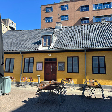 En gammel, gulmalt murbygning på et torg.