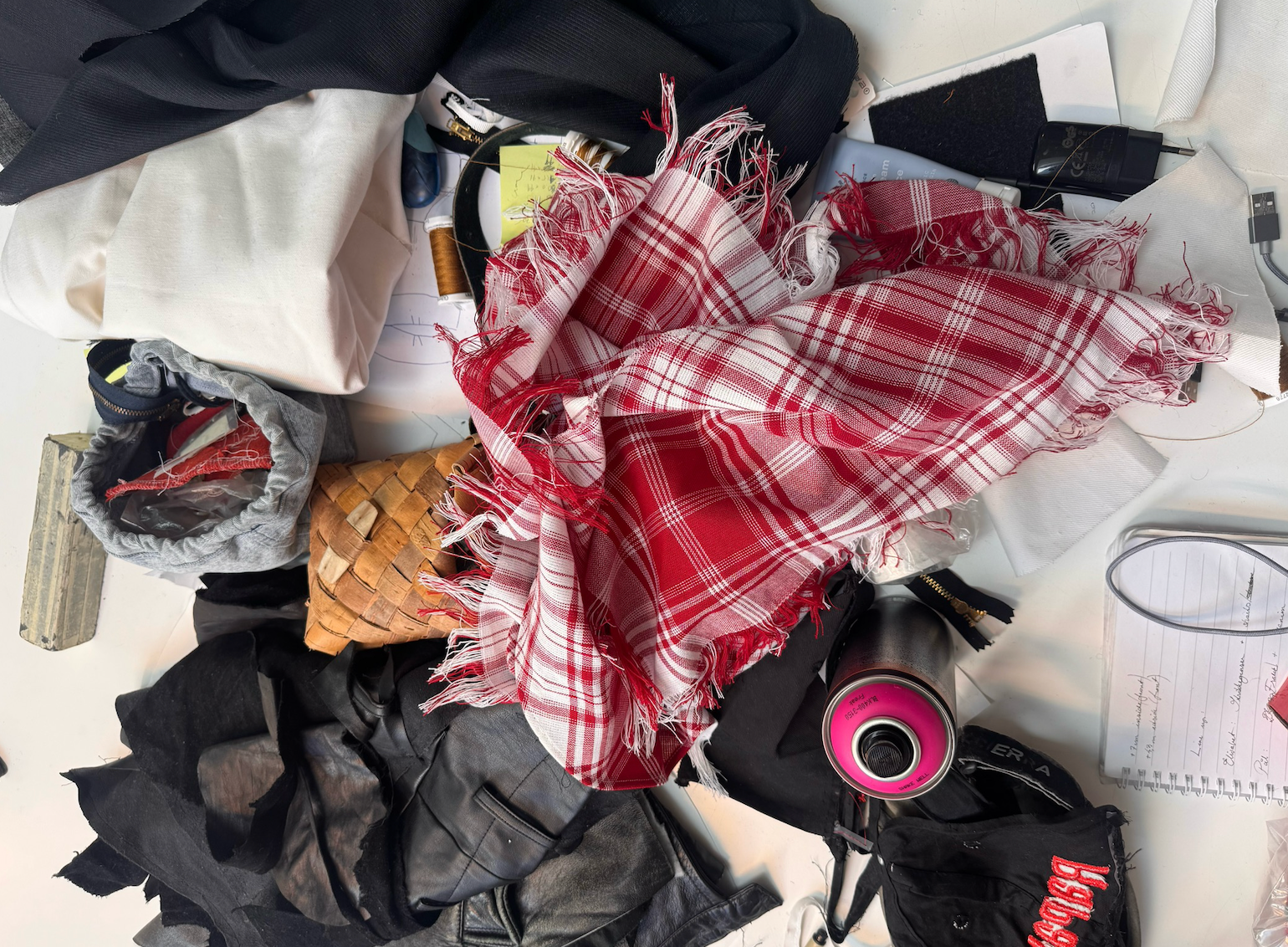 Gulv fylt av ymse rot – stoff, sprayflaske, trådrulle, antekningsblokk mm.