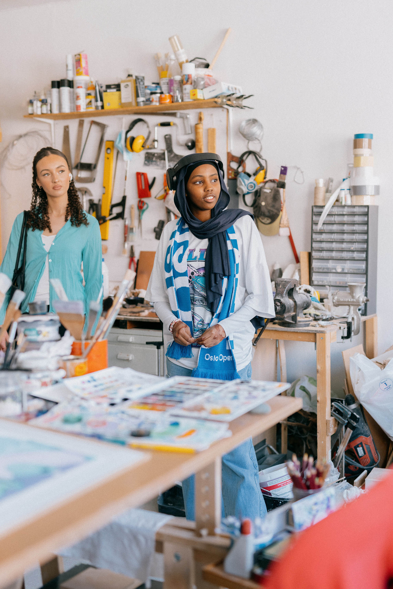 Two young women by a work table with painting equipment.