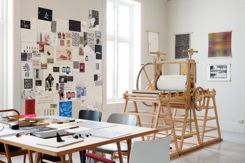 Tretrykkpresse omgitt av trykk og utskriftsutstyr.