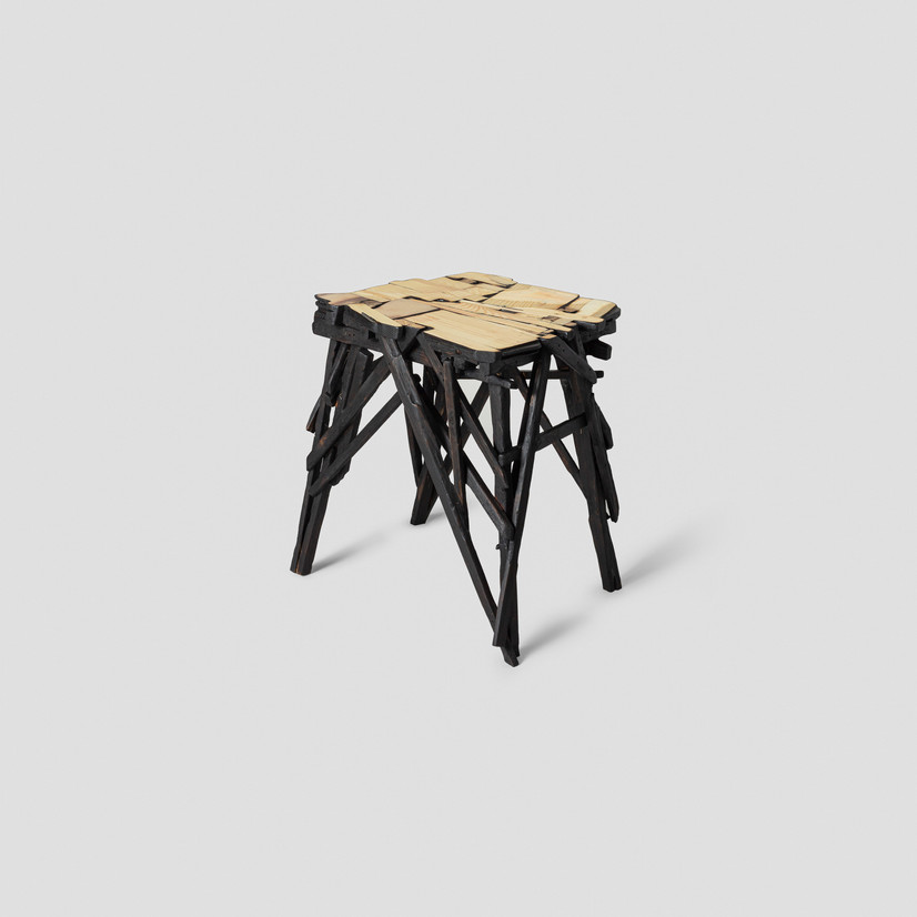 Krakk av mange trebiter, svart brennt, kaotisk konstruksjon, med rett flate som danner en mosaik av trebiter