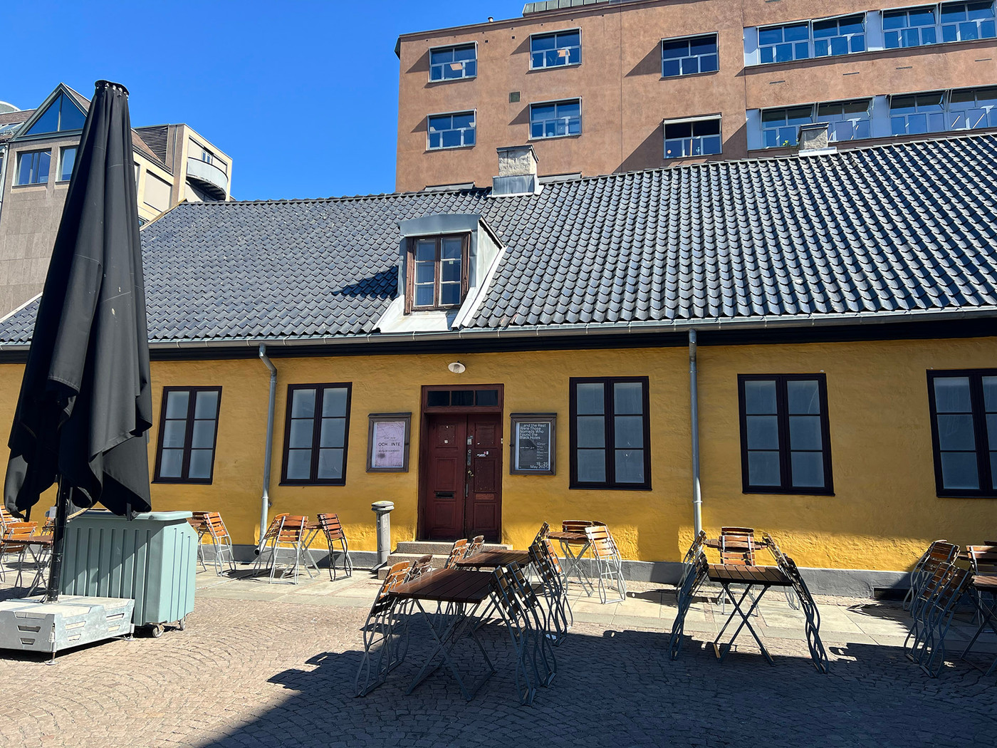 En gammel, gulmalt murbygning på et torg.