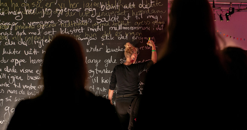 Bildet beskriver meg, der jeg står og gjør en performance, der jeg skrev tekst på veggen direkte løpet av en hel natt, igjen og igjen, over hverandre, til teksten ble vanskelig å lese.